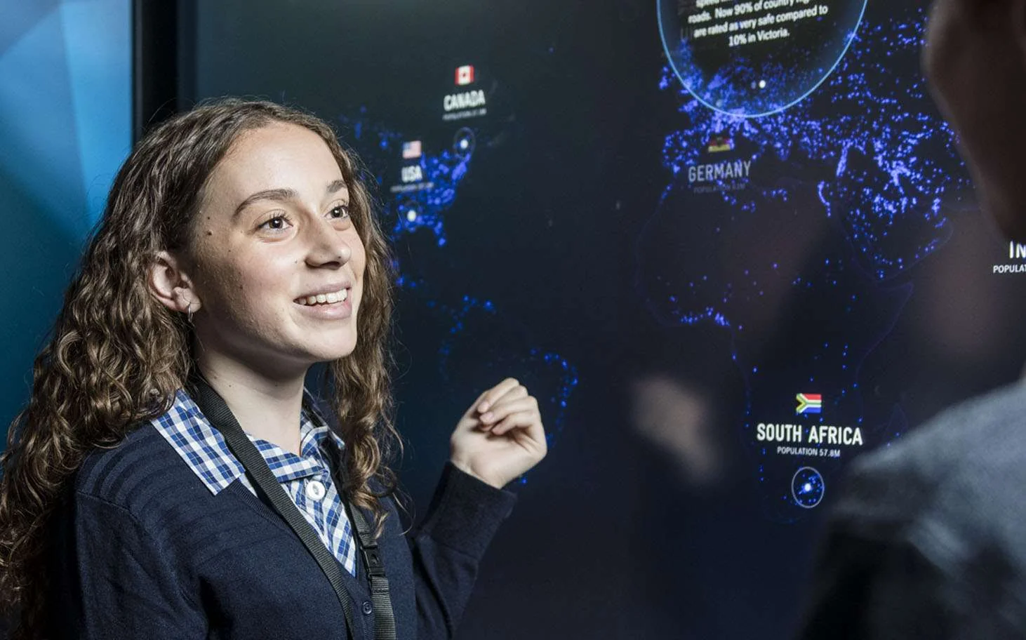 A visitor stands beside a large world-map display comparing road safety in different countries