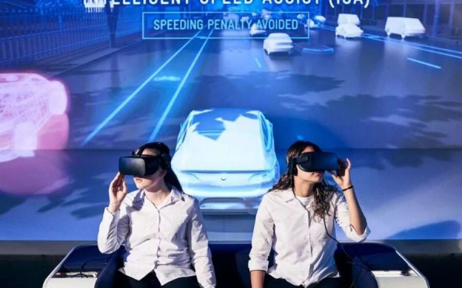 Two visitors wear VR headsets in front of a projected road scene at the Road to Zero exhibition
